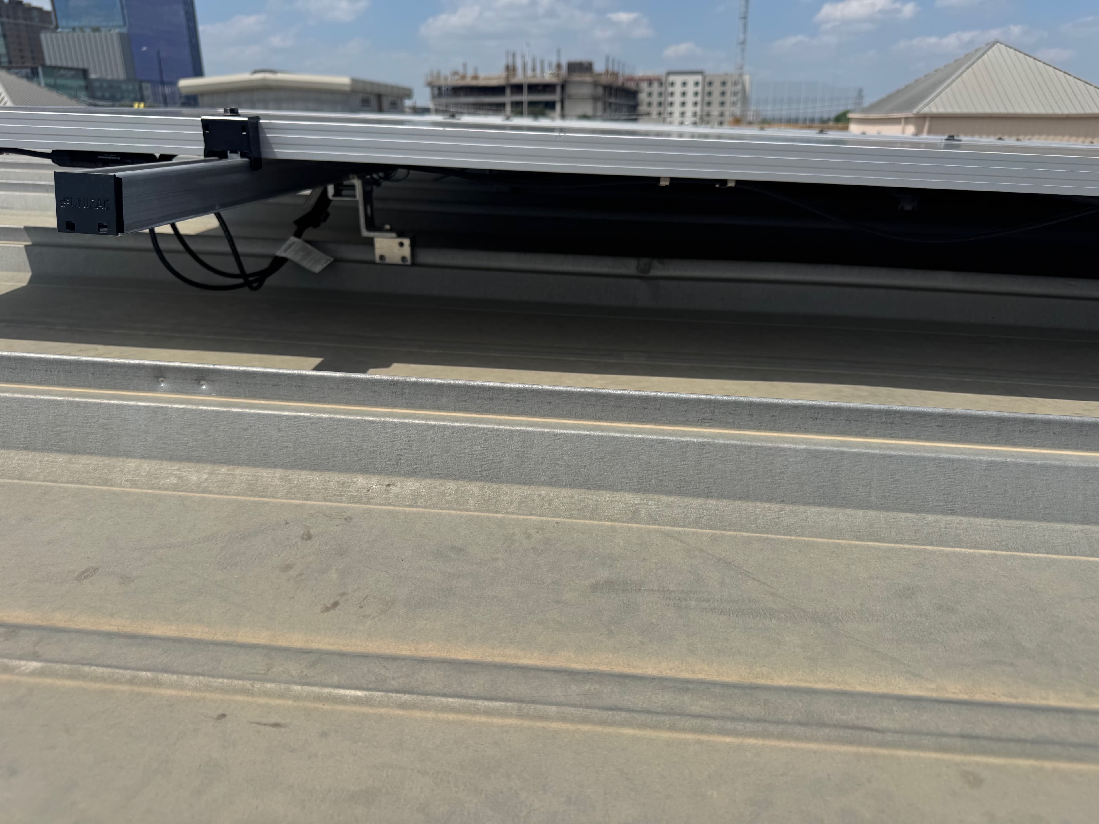 Close-up of Unirac mounting hardware and labeled wiring under a solar module